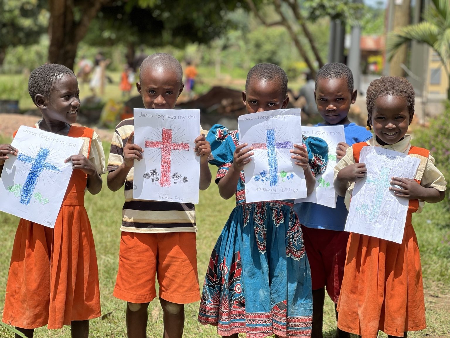 Children holding drawings that say Jesus forgives my sins